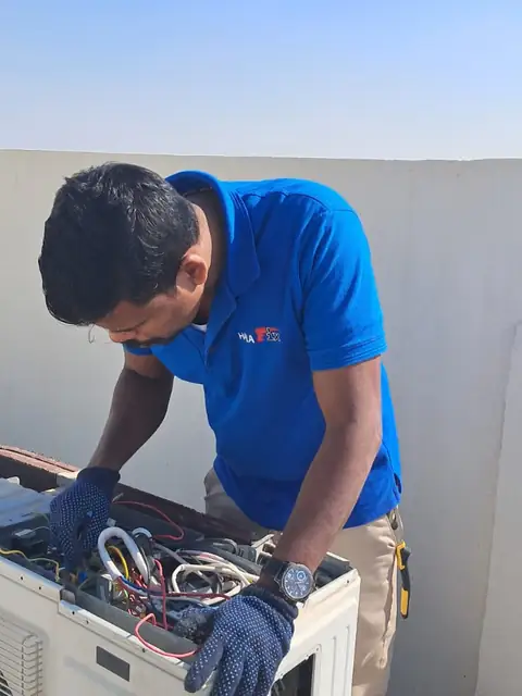 Technician servicing an outdoor AC condenser in Dubai